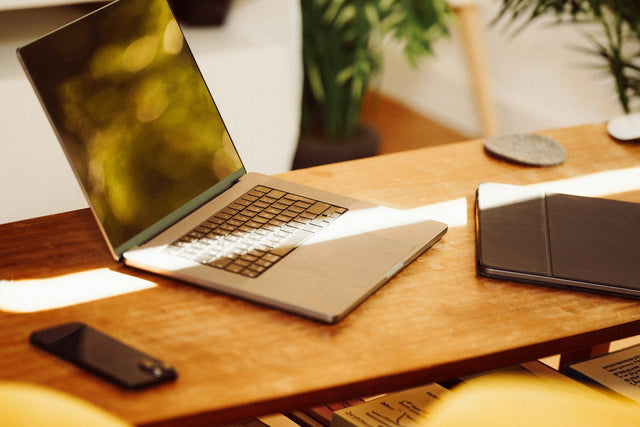 Intelligente Suche nach Möbeln: aufgeklappter Laptop auf einem Holztisch im hellen Wohnraum mit Pflanzen